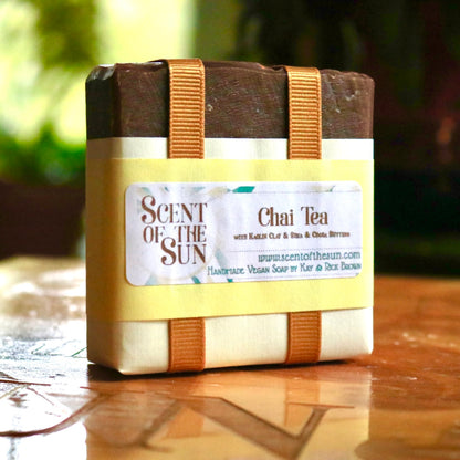 Wrapped bar of plant-based Chai Tea bar soaps, made of vegan ingredients and featuring kaolin clay, shea butter, and cocoa butter. The bar is wrapped in golden-orange ribbon and white paper.