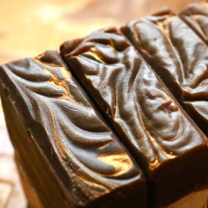 Three bars of dark brown Chai Tea vegan soap with golden swirls running through the top of each individual one.