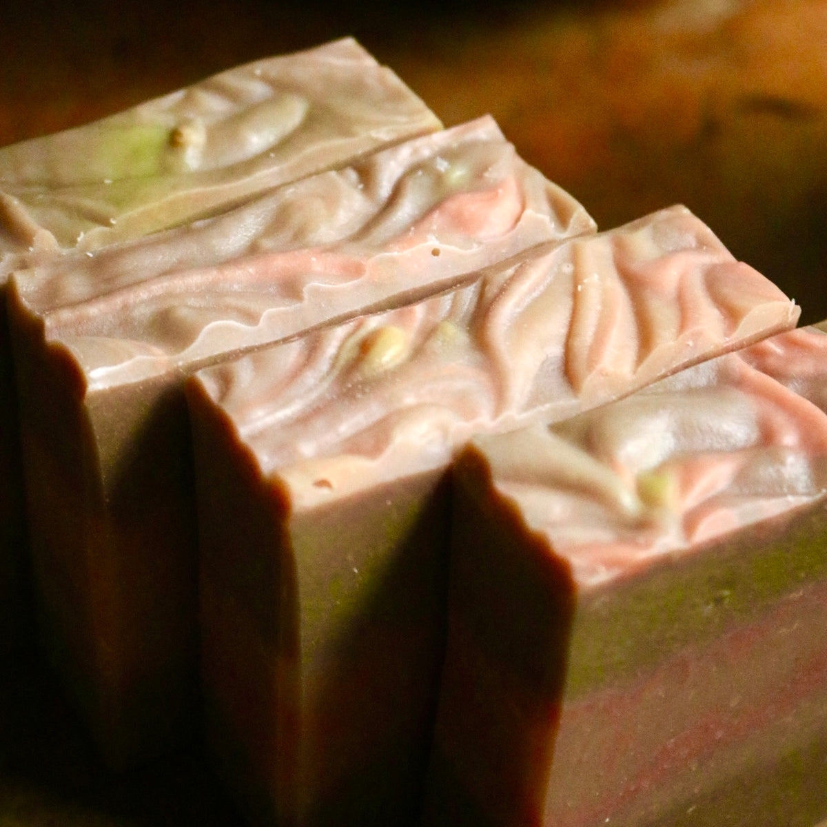 Four bars of plant-based, vegan Sweet Fig soaps seen from above, in a diagonal row with tops showing swirls of pink and yellow.