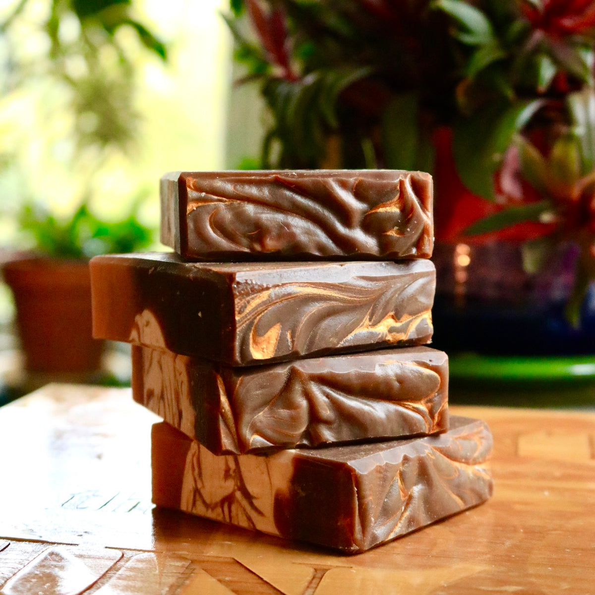 Stack of four plant-based Chai Tea bar soaps atop a wooden base with golden streaks on the top of each vegan bar.