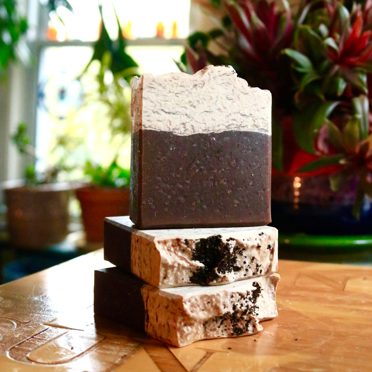 Vegan, plant-based Caffe Mocha soap seen in a group of three, with two bars on their side below one bar standing atop them. Each features kaolin clay, shea butter, and cocoa butter.